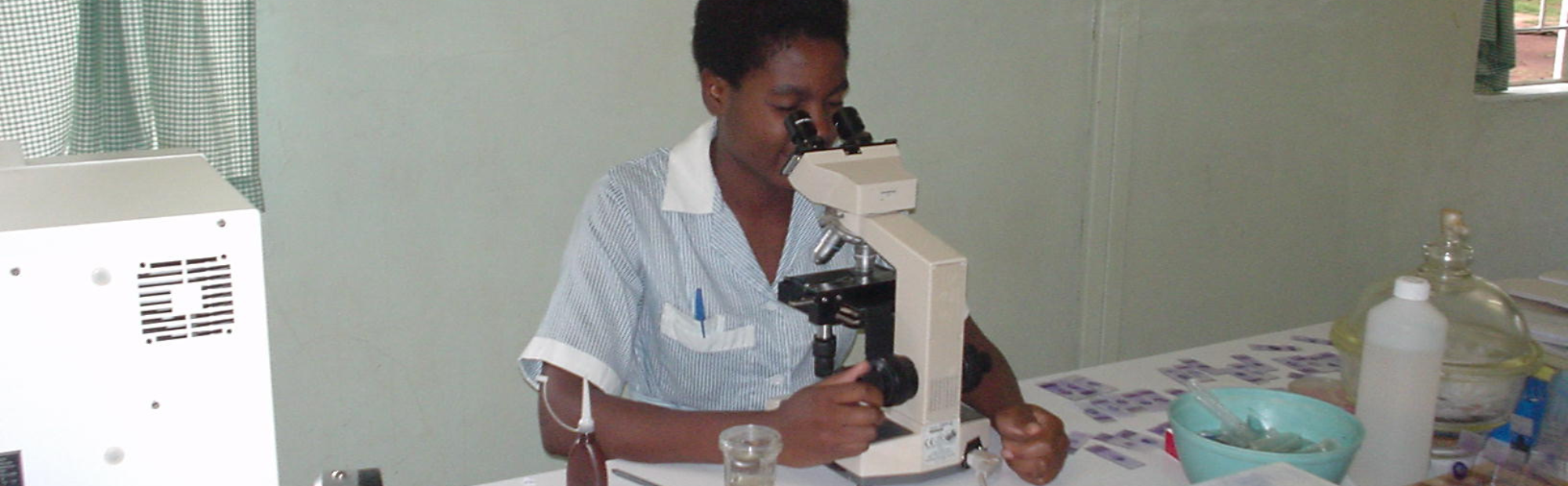 Laboratory professional using a microscope to support diagnostic services in a healthcare facility.